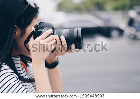 some women hold Dslr camera on hand and take a photo in city 