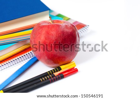 Colored pencils, books, pen, notebooks and an apple
