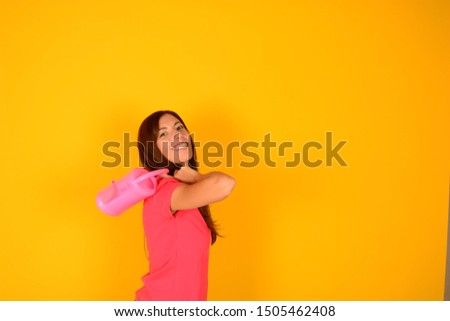 happy woman with smile holds watering can in pink t-shirt on yellow background