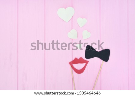 concept of man and woman fallen in love. Female lips and bow-tie with hearts on a pink wooden background with place for text. Idea for wedding, greeting card, Valentines Day