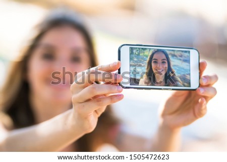 Young girl at outdoors taking a selfie with the mobile