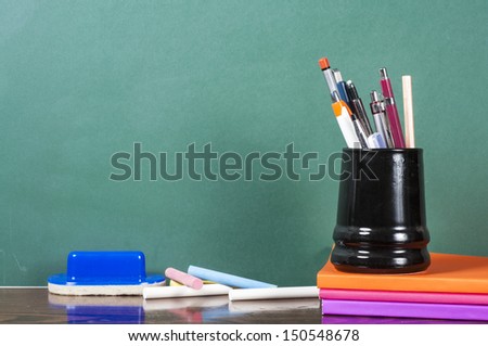 books chalk and penholder in front of green chalkboard Royalty-Free Stock Photo #150548678