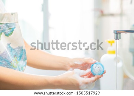 Mother cleaning baby teat and milk bottles with bottle brush. Copy space.