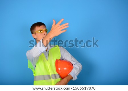 man with glasses in his helmet shows his hand to the side on a blue background