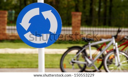 A road sign with bicycles in the background