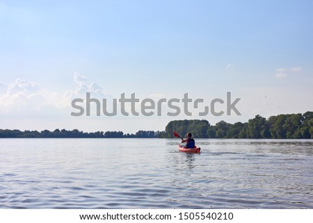 Man in red kayak kayaking in Danube river at spring at sunset