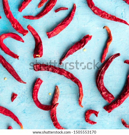 Dried red hot chili peppers on a blue background, overhead square shot