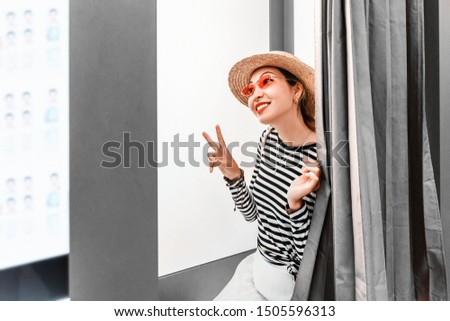 Asian girl having fun and making faces in the photo booth. The concept of small business in the field of photo printing