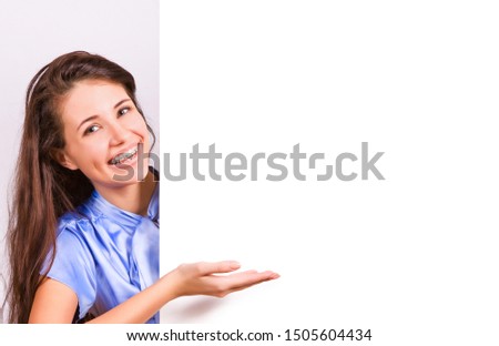 Attractive girl with braces presenting empty board