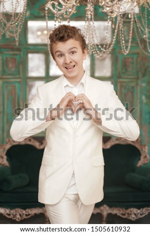 beautiful caucasian teenager boy shows heart love symbol by arms palms alone in white clothes.