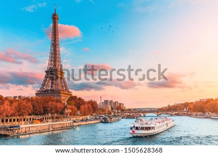 The main attraction of Paris and all of Europe is the Eiffel tower in the rays of the setting sun on the bank of Seine river with cruise tourist ships Royalty-Free Stock Photo #1505628368