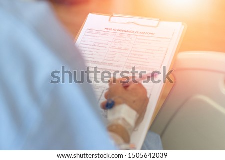 Healthcare insurance business concept. Ageing Patient hand holding pen filling medical health insurance claim form to pay bill in clinical hospital.