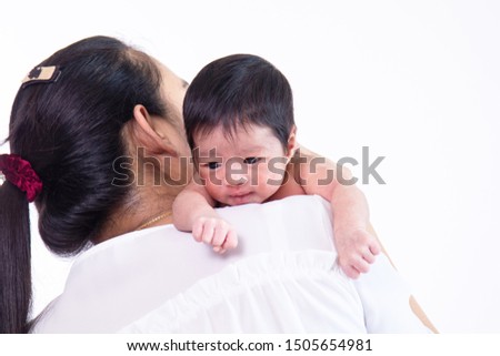 Close up beautiful young Asian mother kissing and hold tiny adorable newborn baby girl 0-1 month on shoulder with caring and love, lifestyle health care newborn at home concept on white background