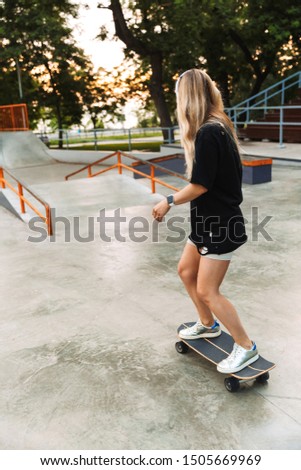 Back view of a funky young girl teenager riding on a longboard at the skatepark