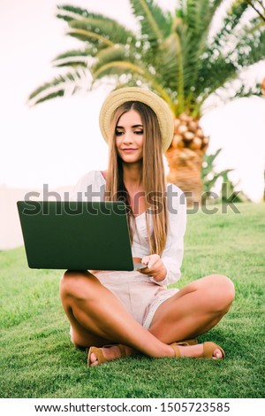 Young woman in straw hat lying on green grass andbrowse in internet with laptop in resort park at s vocation