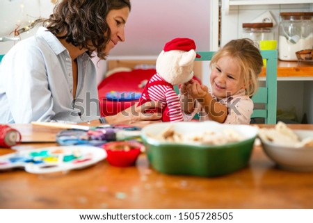 Mother and daughter playing with teddy bear in the kitchen