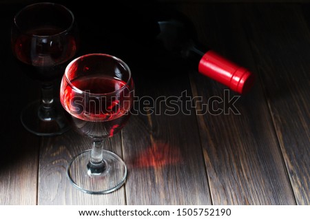Red wine in glasses. Bottle of wine. Dark brown wooden background. Copy space
