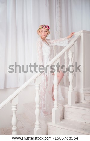 Blonde girl with a bouquet in a white coat with a wreath on her head