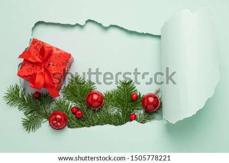 New Year Christmas layout and a big hole on a paper background mint color. Christmas tree toys fir branches and a gift with a red bow on a blue bright background. Minimalism. Christmas concept.