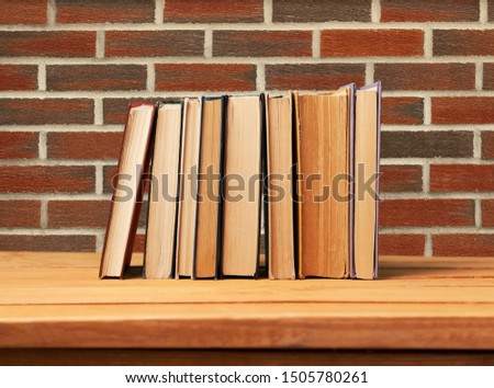 Vintage books on wooden table over retro wallpaper background