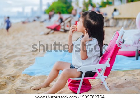 Little girl sitting on a beach chair look at the sea