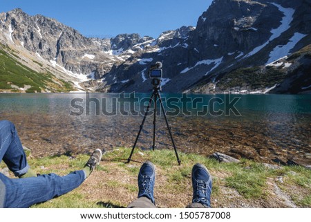  Photographers take scenic views on mountains lake. Camera on tripod