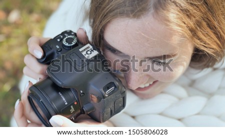 The girl takes pictures of nature in the park in the summer. Hands with a photo camera close-up.