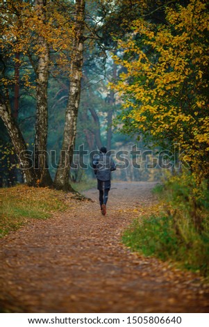 Photo from back of running athlete in autumn park