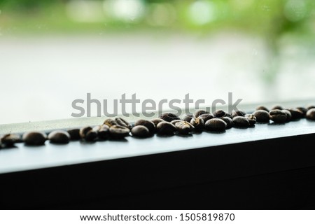 Roasted coffee beans on window with green bokeh light background