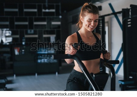 On exercise bike. Photo of gorgeous blonde woman in the gym at her weekend time.