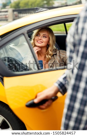 Photo of man opening taxi door where happy blonde sits on summer.