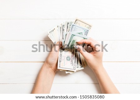 Businesswoman's hands counting one hundred and various dollar bills on wooden background. Salary and wage concept. Top view of Investment concept.