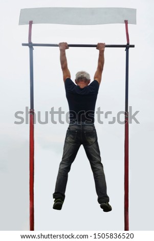 Muscle man making pull-up on horizontal bar on blue sky background. back view. 