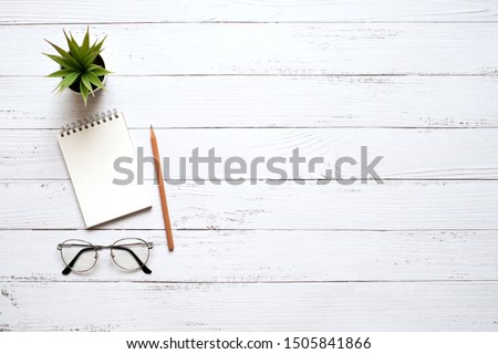 Work space office white wooden table desk with white blank notepad and supplies, flat lay with copy space, top view