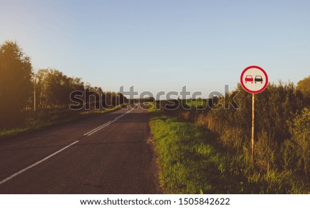 Vintage photo of country asphalt road with traffic sign "No overtaking"