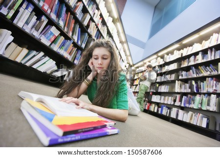 Female university student studying on library floor
