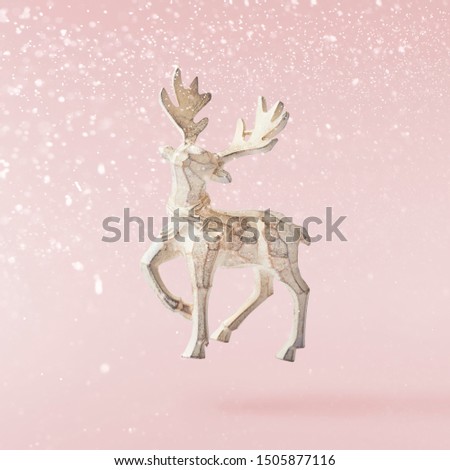 Christmas card conception. Christmas  toy deer decoration falling in the air on pink background. Levitation concept. High resolution image