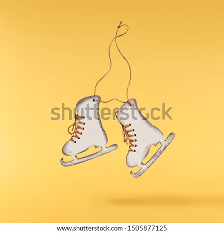 Christmas card conception. Christmas  toy skates decoration falling in the air on yellow background. Levitation concept. High resolution image