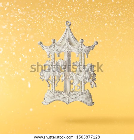 Christmas card conception. Christmas  toy carousel decoration falling in the air on yellow background. Levitation concept. High resolution image