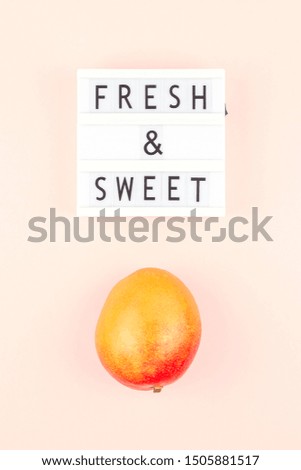 Mango fruit in creative conceptual top view flat lay composition with lightbox with Fresh and sweet text isolated on pink background in minimal style with copy space. Pop art concept poster