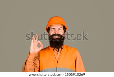 Repair, construction, building. Male builder or manual worker in helmet shows ok sign. Mechanical worker making gesture okay. Construction worker in hard hat. Bearded man in hardhat with perfect sign.