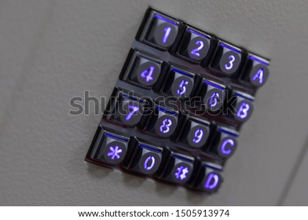 Black metal buttons with blue shiny lights numbers, including number sign hashtag and asterisk, A B C letters on gray abstract surface, diagonal view.