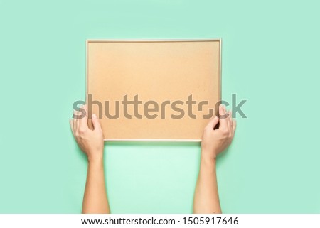 Woman holding empty frame with cork board for text, mock-up frame, isolated on neo-mint background. frame mockup