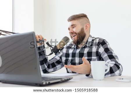 Radio, DJ, blogging and people concept - Smiling man sitting in front of microphone, host at radio