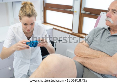 female medical doctor taking a picture of injured leg