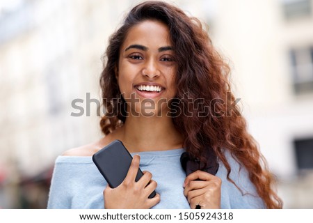 Close up front portrait of beautiful young Indian woman smiling with mobile phone Royalty-Free Stock Photo #1505924318