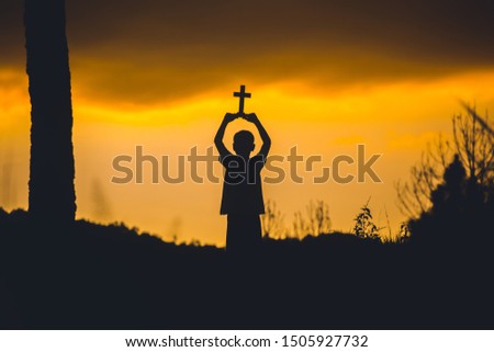 Children holding christian cross with sunset background,christian silhouette concept.