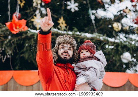 portrait of happy family: Father and baby Son On Winter Vacation near Christmas Tree. Father giving son ride on back in park. Happy, joyful family.