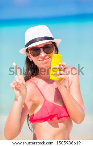 Young woman apply cream on her nose on the beach