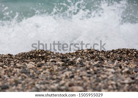 A sea foam is white the during a surf. It is the rest on the rocky beach. The boundary between land and water showned here
